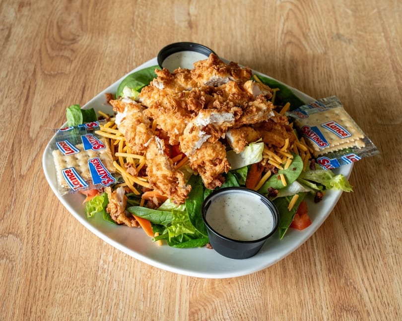Crispy fried chicken salad with cheese, bacon, lettuce, tomato, and two packets of Saltines.