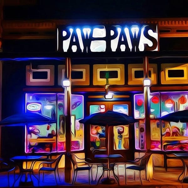 Vibrant, neon-lit "Paw Paws" restaurant exterior at night with outdoor seating and umbrellas.